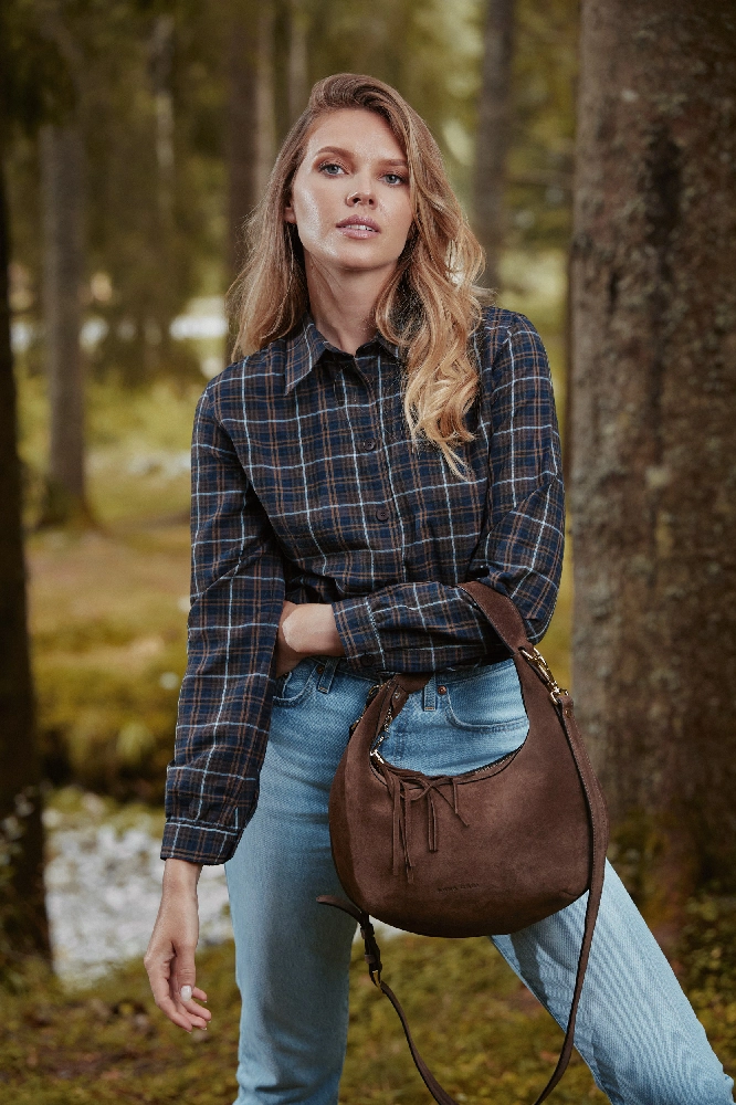 geantă maro din piele întoarsă purtată cu blugi și cămașă în carouri